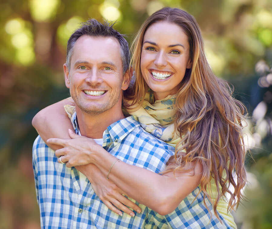 couple smiling with female in back